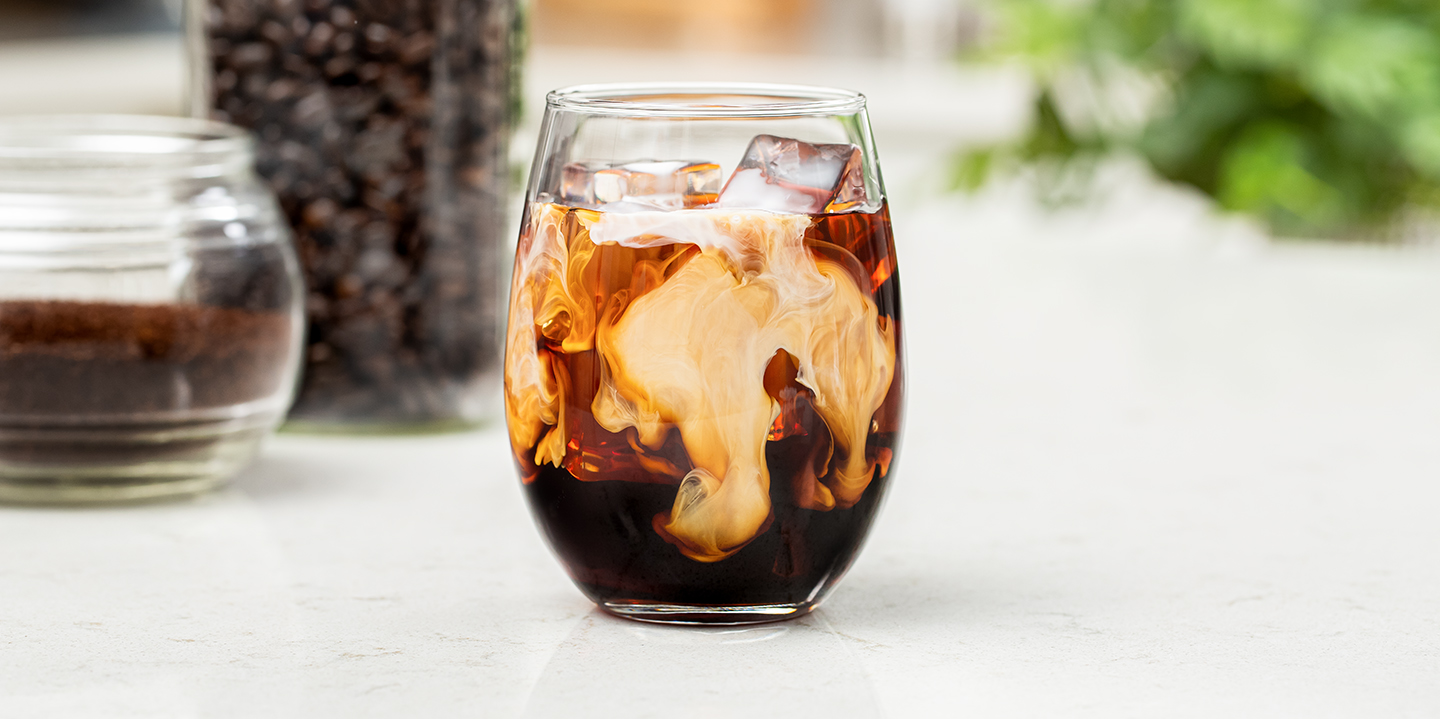 cold brew coffee with cream served over ice in a glass on counter