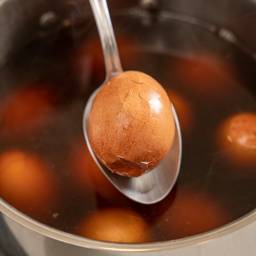 Cracked Green Tea Leaf Egg on a spoon above bowl