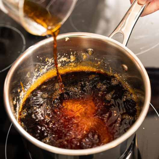 Adding coffee concentrate and lemon juice mixture to melted sugar